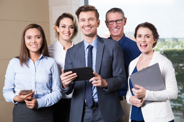 smiling-business-team-standing-conference-room-1-1